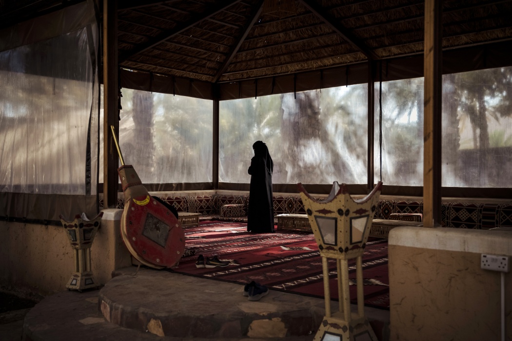 Inside a restaurant, a Saudi woman prays.